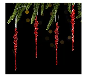 Vue détaillée de quatre ornements stalactites rouges pailletés sur une branche de sapin.
