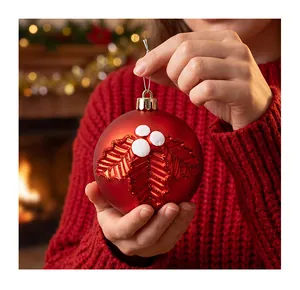 Detailed close-up of a red festive Christmas bauble with embossed holly leaf design