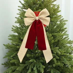 Dettaglio di un grande fiocco natalizio in juta e velluto rosso su un albero.