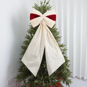 Dettaglio di un grande fiocco natalizio in velluto crema e rosso su un albero di Natale.