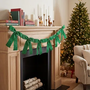 Close-up of emerald green glitter bow garland hung on a festive Christmas fireplace mantel