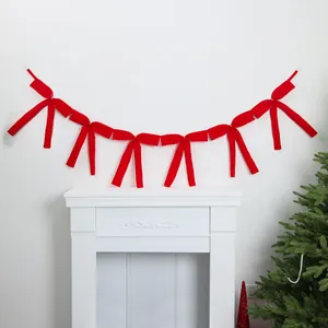 Elegant red ribbon bow garland decoration hanging above a white fireplace mantel scene