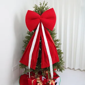 Close-up of a large red Christmas bow with white streamers on a tree decoration.