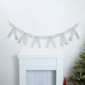 Elegant silver glitter bow garland hung as festive background decoration over a white mantel