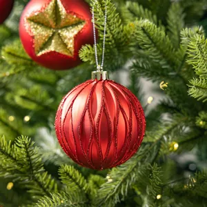 Textured red Christmas ornament bauble hanging on a festive green pine tree branch.