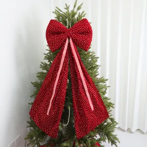 Detail of a large red velvet Christmas bow tree topper with gold heart print and ribbons.