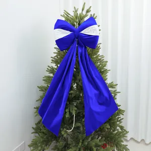 Grande fiocco decorativo blu reale e bianco sulla cima di un albero di Natale foto