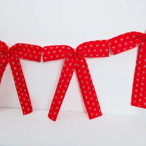 Detail of a festive red ballet-style ribbon bow garland with silver glitter patterns.