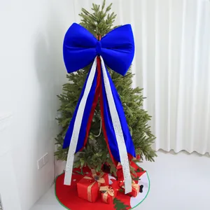 Large blue velvet Christmas bow with red and white streamers on a decorative holiday tree