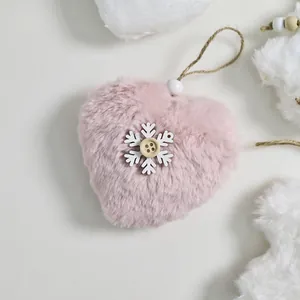 Close-up of a soft pink plush heart ornament with a white snowflake and twine loop.