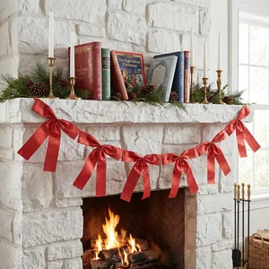 Festive red satin bow garland decoration hanging on a white stone fireplace mantle.