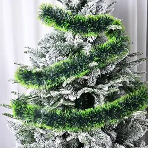Close-up view of vibrant green Christmas tinsel garland wrapped on a flocked tree