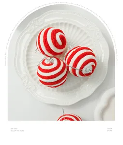Detail van rood-wit gestreepte pluche kerstballen op een decoratief wit bord in de schaal