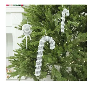 Silver and white glitter candy cane ornaments hanging on a lighted Christmas tree