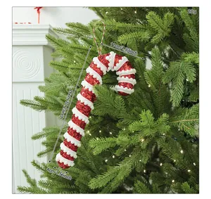 Close-up of a red and white glitter candy cane ornament hanging on a Christmas tree.