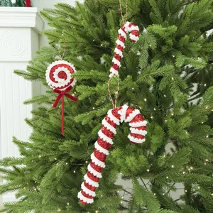 Festive red and white foam Christmas candy ornaments hanging on a lush green tree.
