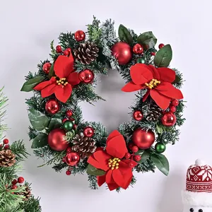 Corona di Natale artificiale con stelle di Natale rosse, pigne e palline per la porta.