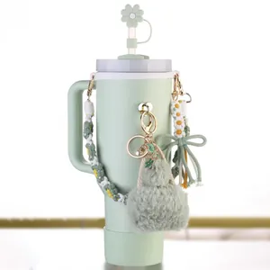 Detalle de accesorios de vaso verde menta con tapa de pajita de flor y amuleto