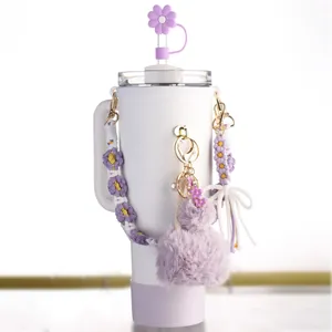 Detalle de la tapa de pajita de flor púrpura y la correa tejida en un vaso térmico blanco