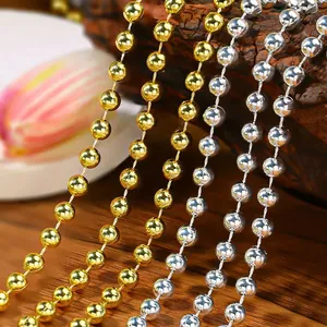 Cadenas de perlas navideñas doradas y plateadas sobre un fondo de madera rústica