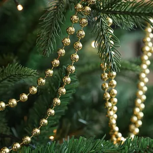 Guirnalda de perlas doradas sobre ramas de abeto para la decoración del árbol de Navidad.