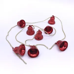 Detalle de guirnalda de campanas navideñas rojas con cadena de perlas doradas.