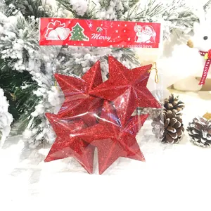 Set aus verpackten roten Glitzer-Weihnachtsstern-Anhängern vor festlichem Baum
