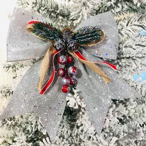 Fiocco di Natale argento scintillante con pigna e bacche rosse su un albero innevato