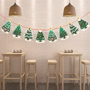 Guirlande de Noël festive en papier avec sapins suspendus sur un mur de briques.