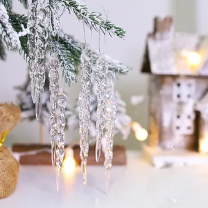 Adornos de carámbanos de acrílico transparente en un árbol de Navidad nevado.