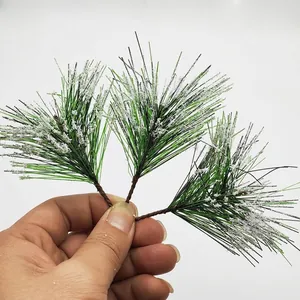 Nahaufnahme künstlicher PVC-Kiefernnadeln mit Schneespitzen für Weihnachten