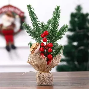 Close-up van een mini kunstmatige kerstboom met rode bessen en een voet van jute