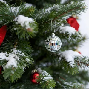 Close-up van een zilveren discobal ornament aan een prachtige besneeuwde kerstboomtak