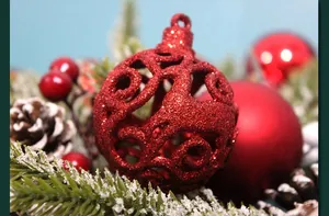 Close-up of red hollowed-out Christmas ball with glitter texture and pinecone detail
