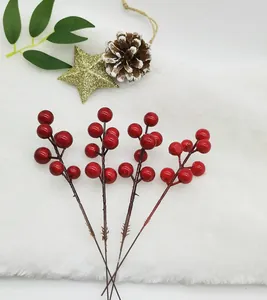 Detailed view of four artificial red berry sprigs on white faux fur with festive props