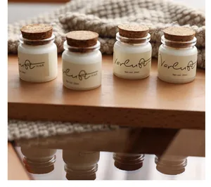 Close-up of four small scented candle jars with cork lids presented on a wooden surface