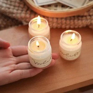 Three lit scented candle jars in a warm, cozy setting with a wooden background.