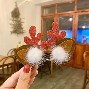 Macro view of cute glittery reindeer antler hair clips with white faux fur poms.