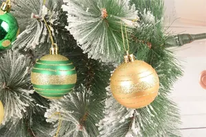 Vista dettagliata di palline di Natale verdi e oro con strisce glitterate su albero innevato