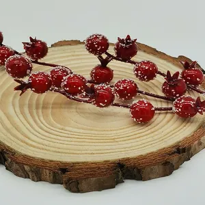 Artificial red berries with frosty snow coating for Christmas decoration on rustic wood slice