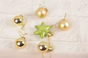 Dettaglio di palline di Natale dorate e un ornamento a stella verde su sfondo bianco