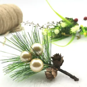 Close-up of mini artificial pine branch with gold pearls and pine cones for Christmas décor