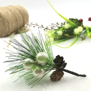 Detailed macro view of a mini artificial pine needle with white pearls and small pinecones.