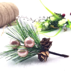 Close-up detail of artificial Christmas pine needle with pink pearls and pine cones.