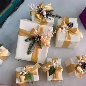 Cajas de regalo decorativas de Navidad blancas con cintas doradas, piñas y bayas