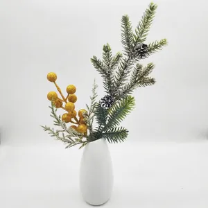Detailansicht von künstlichen Tannennadeln mit goldenen Beeren und Zapfen in weißer Vase