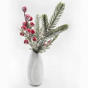 Detailed macro view of artificial pine needles and marbled red berries in a white ceramic vase