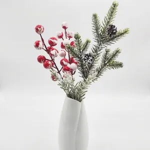 Nahaufnahme von künstlichen Tannennadeln mit festlichen roten Beeren und Zapfen