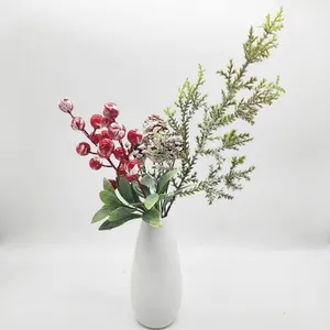 Close-up view of decorative artificial Christmas pine needles and red berries in white vase
