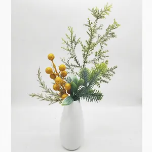 Detailed view of artificial Christmas pine needle picks and golden berries in a white vase